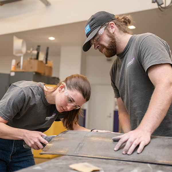 Two Powercat Motorsports team members working on a part for the car